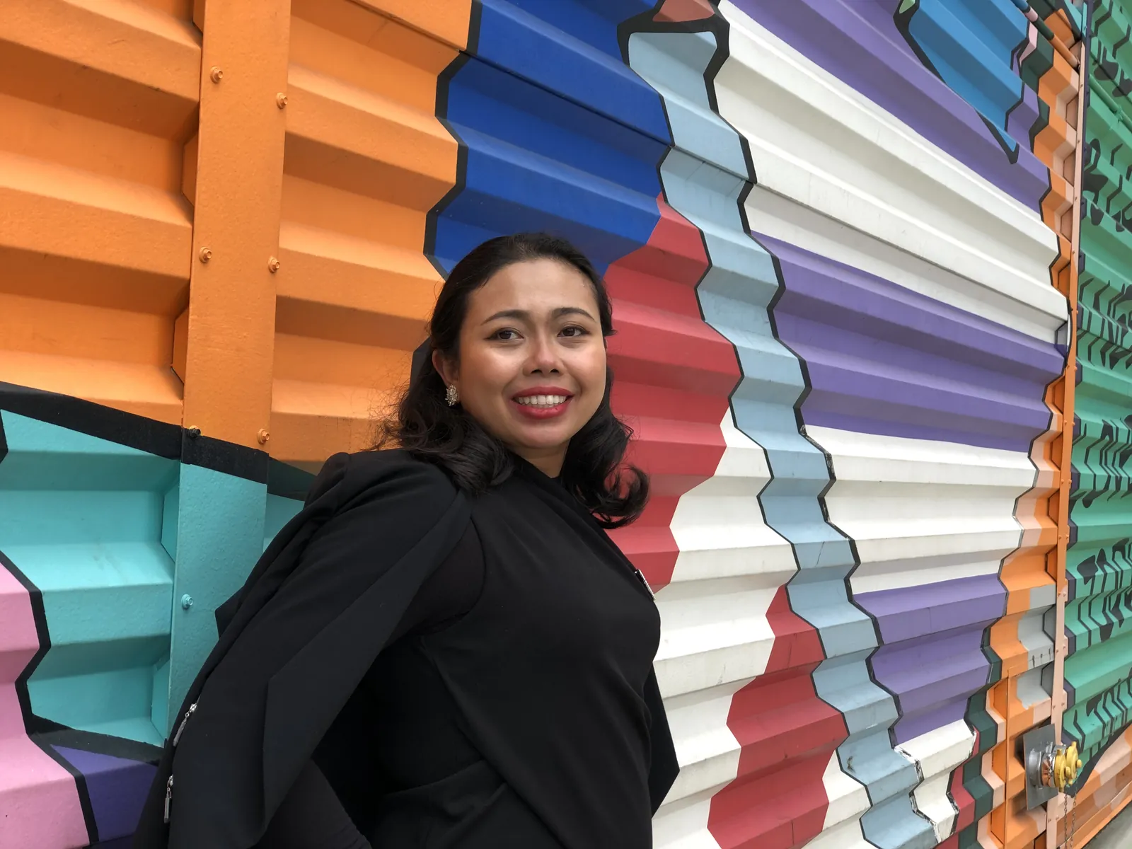 Krittaya smiling in front of a brightly painted wall