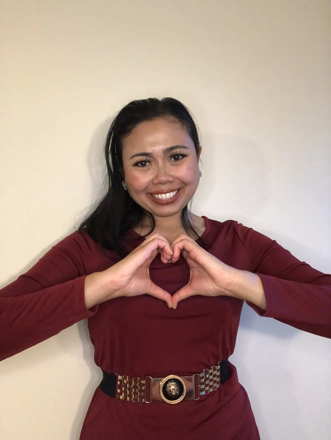 Krittaya making a heart shape with her hands, wearing a burgundy dress