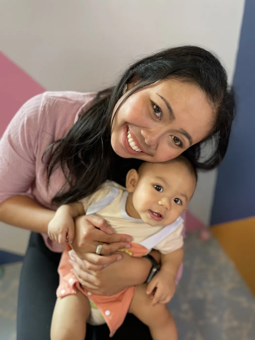 Krittaya Kongkaluang smiling and hugging a happy baby on her lap